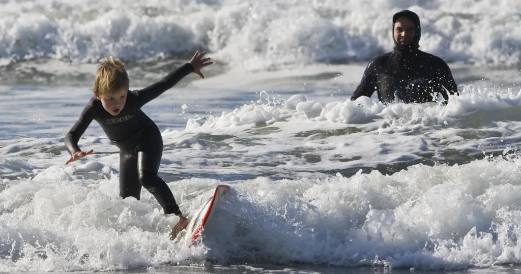 Two kids sharing semi-private surf lesson on island beach