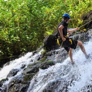 Adventurers rappelling down a tropical waterfall cliff