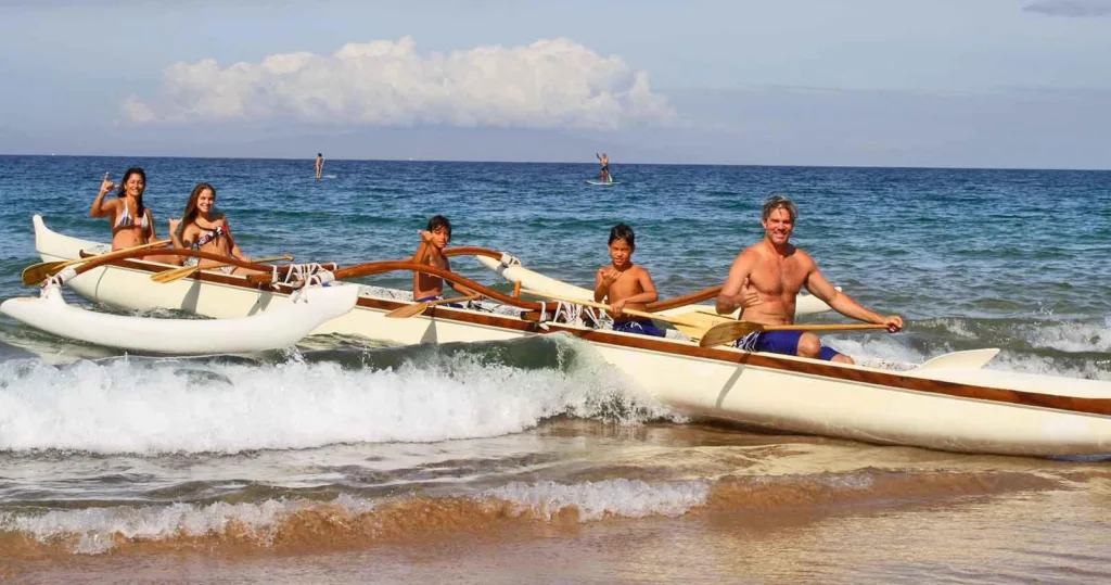 Group paddling Hawaiian outrigger canoes near coral reefs