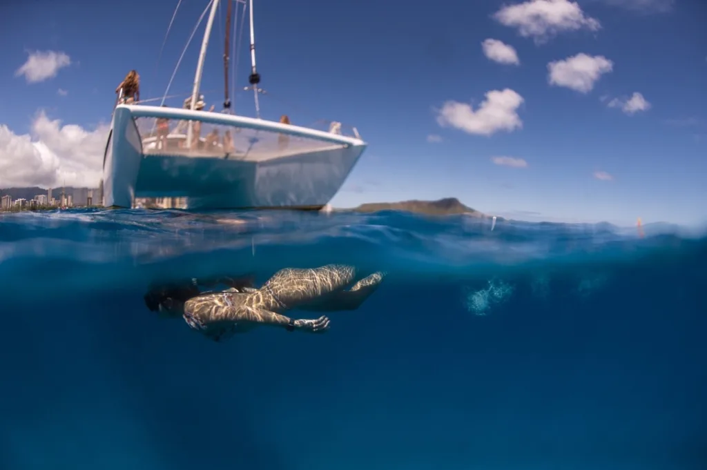 People swimming, snorkeling, and sailing in tropical ocean