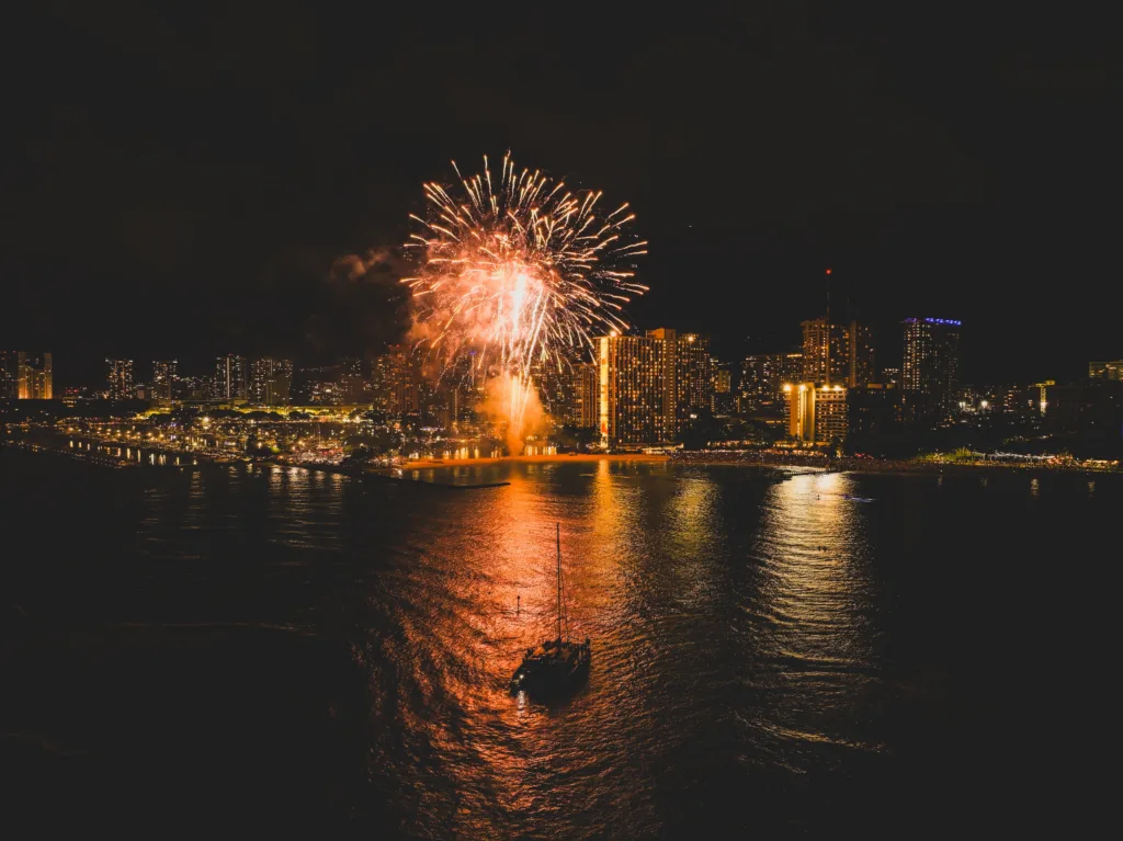 Sailboat cruising with Waikiki fireworks at sunset
