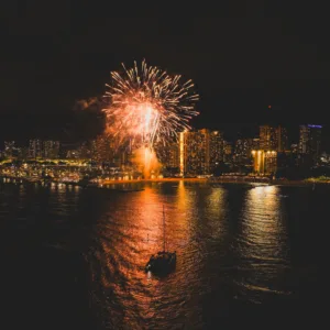 Sailboat cruising with Waikiki fireworks at sunset