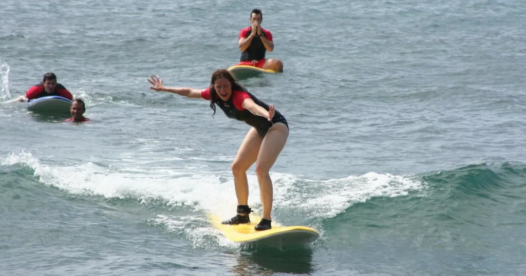 Instructor guiding two students during a surfing lesson