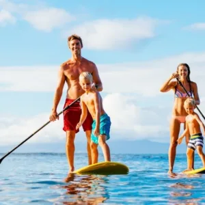 Person paddling on stand-up board across clear water