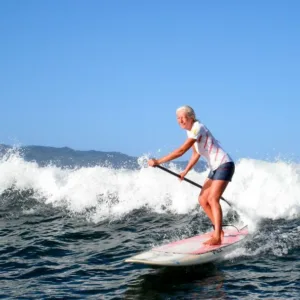 Instructor giving private stand-up paddleboard lesson on calm sea