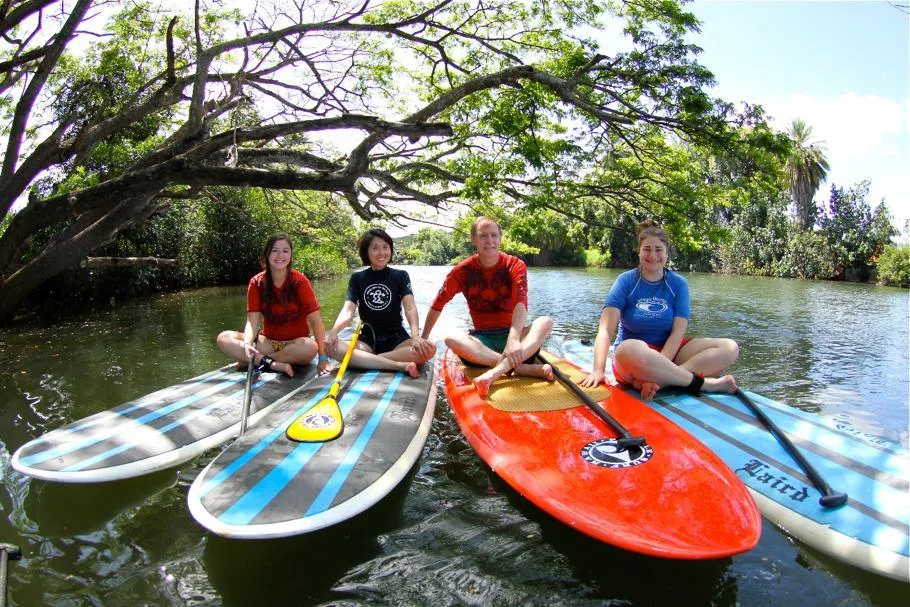 Beginners receiving group instruction during first stand-up paddleboard lesson