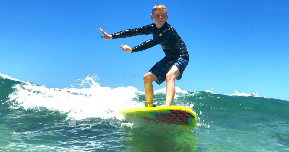 Child learning to surf with private instructor support