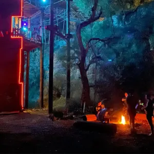 Kids navigating night ninja adventure course under lights