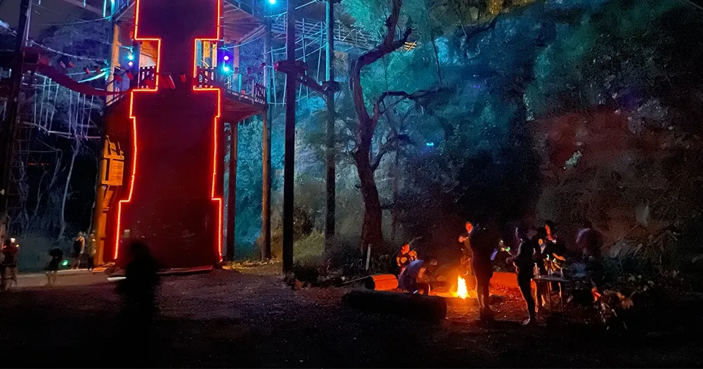 Kids navigating night ninja adventure course under lights