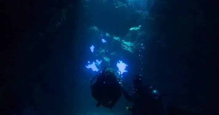 Scuba divers exploring underwater lava formations at Lanai Cathedrals