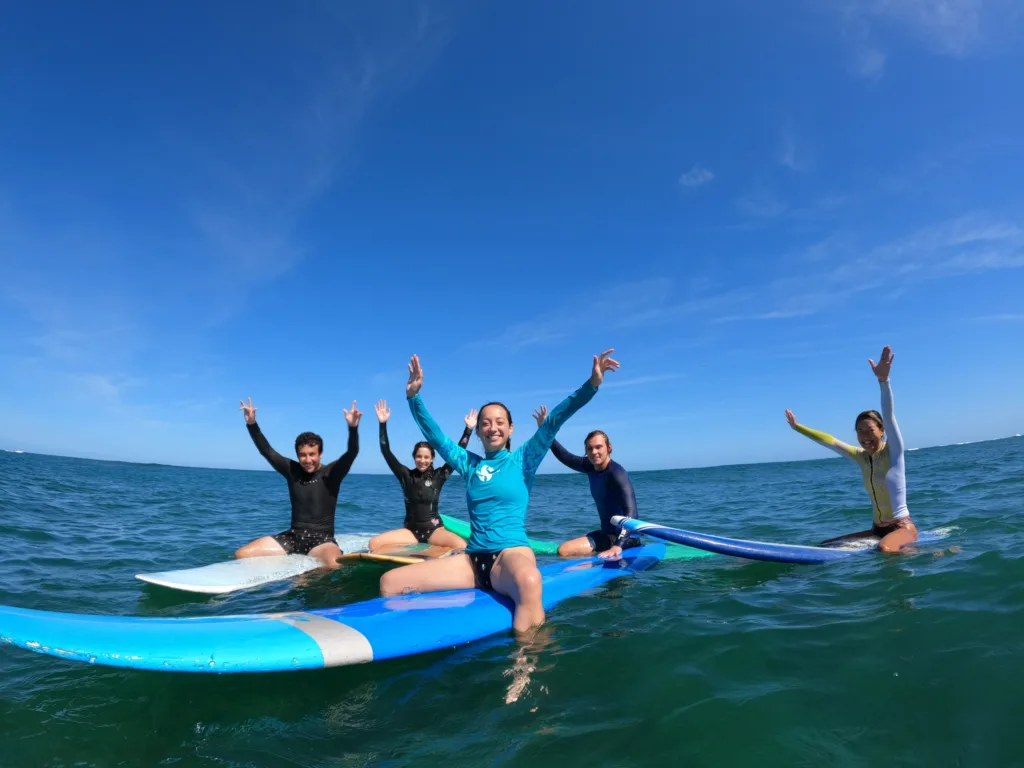 Beginner group enjoying surf lesson on sunny island beach