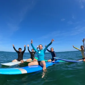 Beginner group enjoying surf lesson on sunny island beach