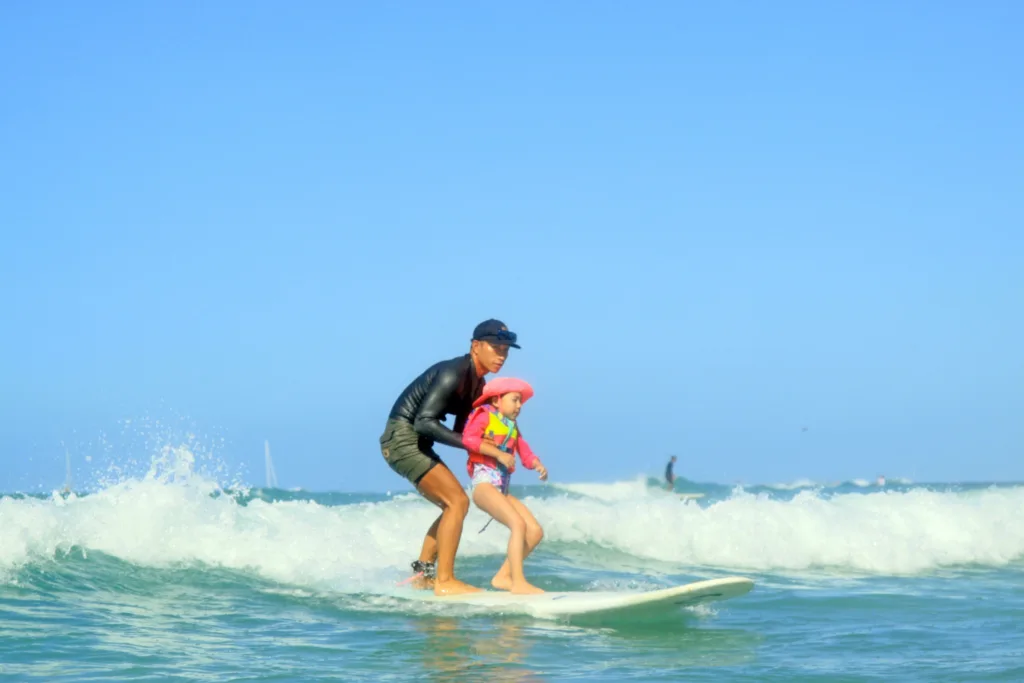 Instructor giving private surf lesson on sunny beach