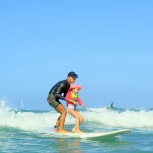 Instructor giving private surf lesson on sunny beach