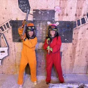 People breaking objects for stress relief in rage room