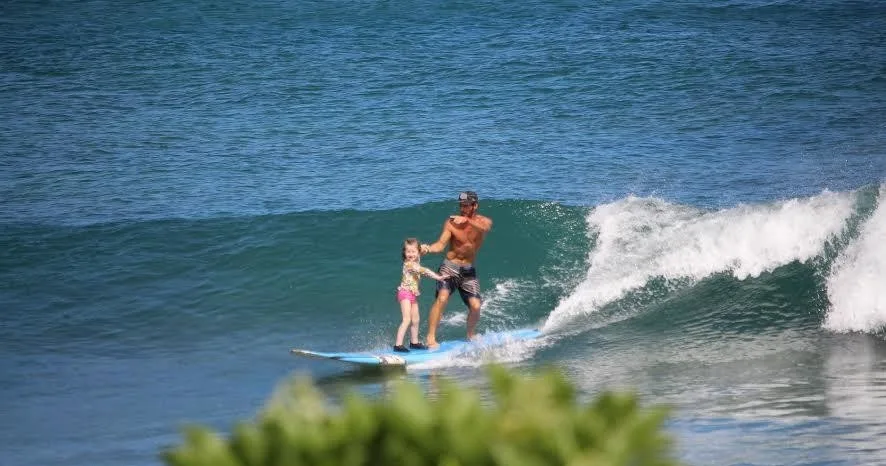 Individual practicing surfing on gentle island waves near shore
