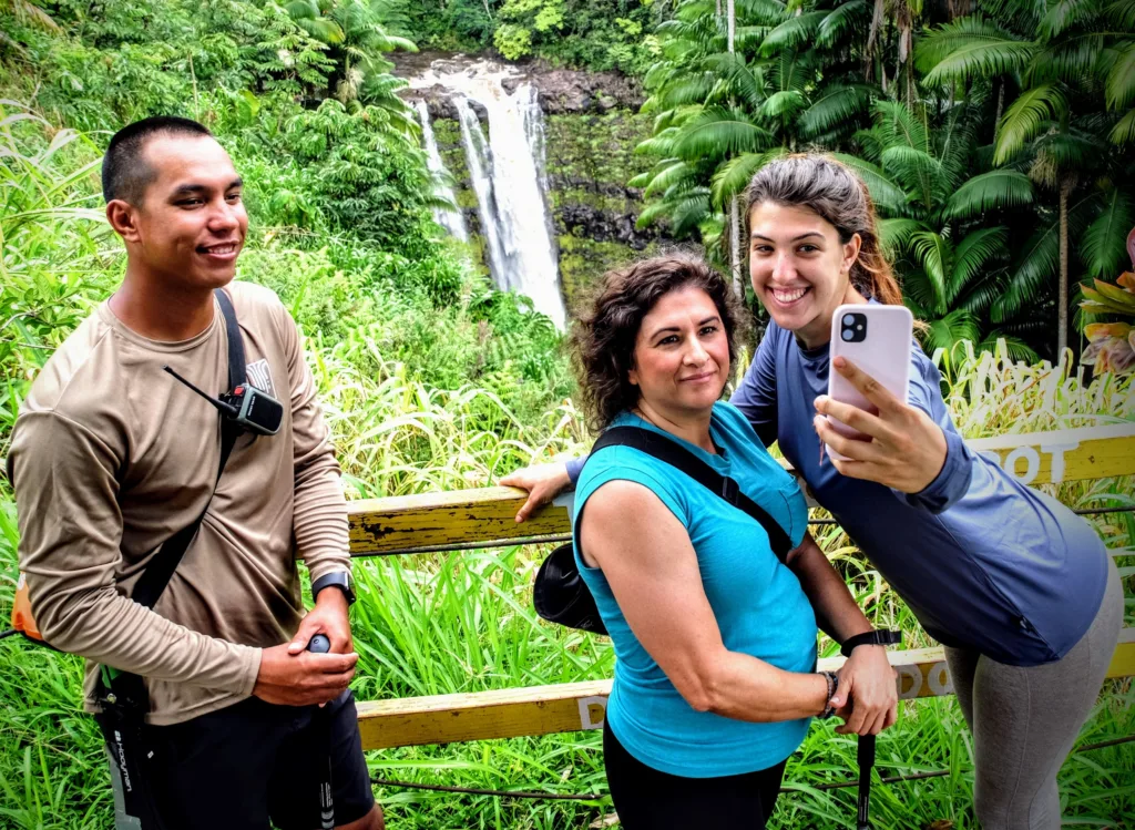 Hikers walking along a lush waterfall trail in a tropical forest