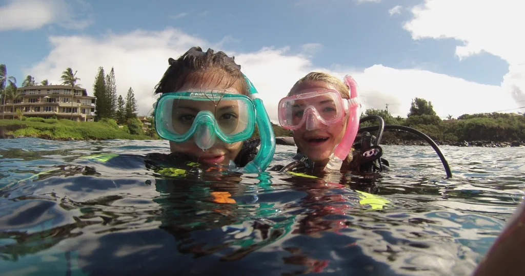 Divers exploring coral reefs at Tunnels shore dive