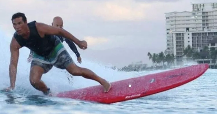 Surfer receiving advanced longboard lesson from champion instructor
