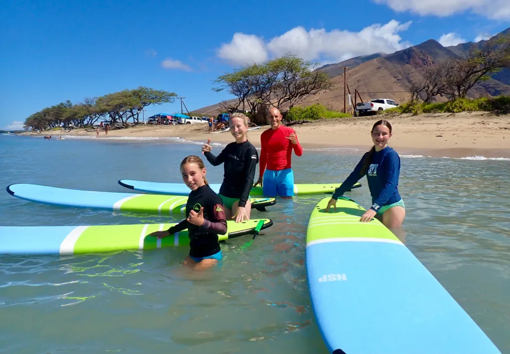 Family learning to surf together on gentle beach waves