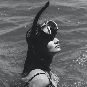 Set of snorkel mask, fins, and snorkel resting on sand