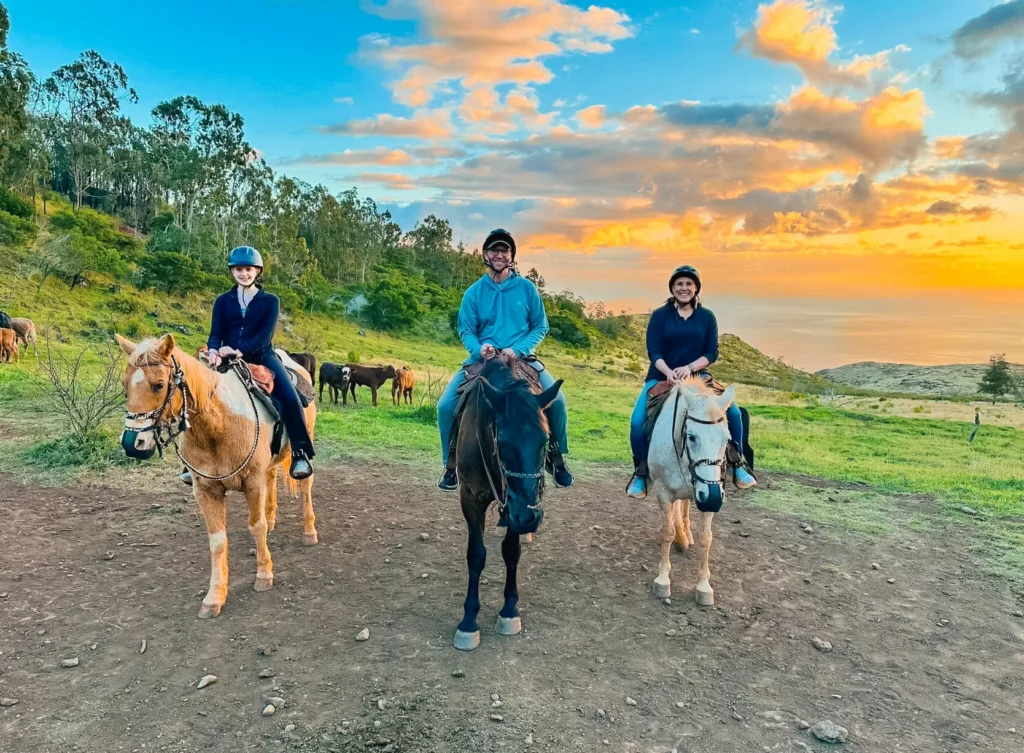 Group horseback ride during sunset with mountain views
