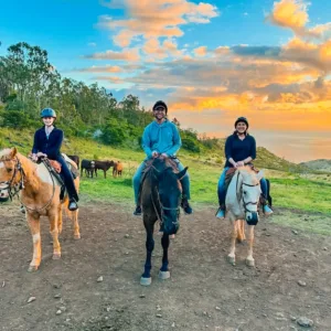 Group horseback ride during sunset with mountain views