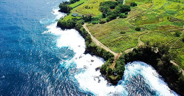 Boat cruising near Onomea Waterfall cliffs in Hawaii