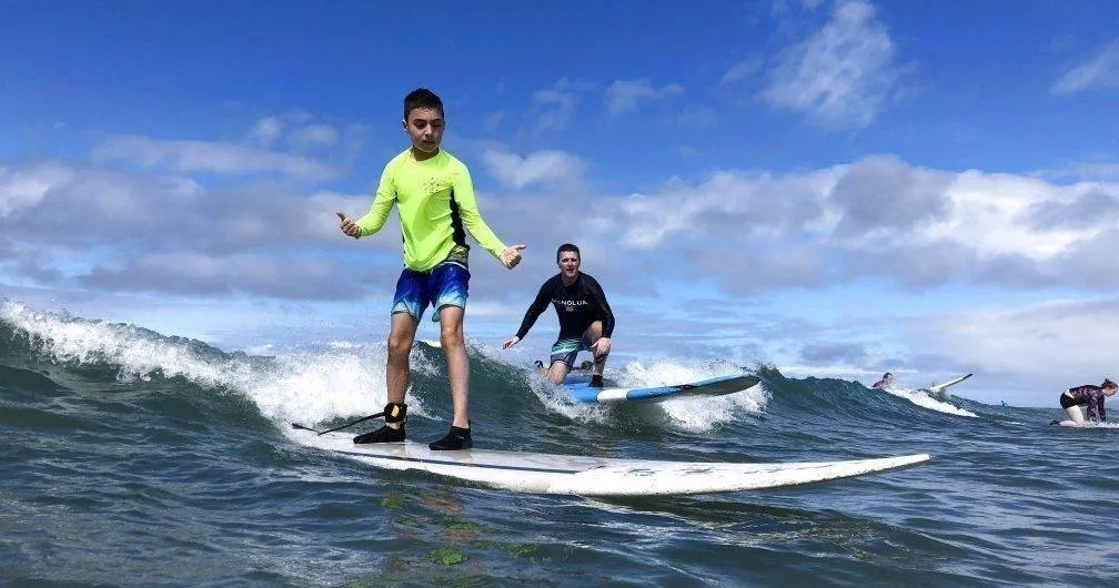 Surf class participants learning to ride waves on Maui beach