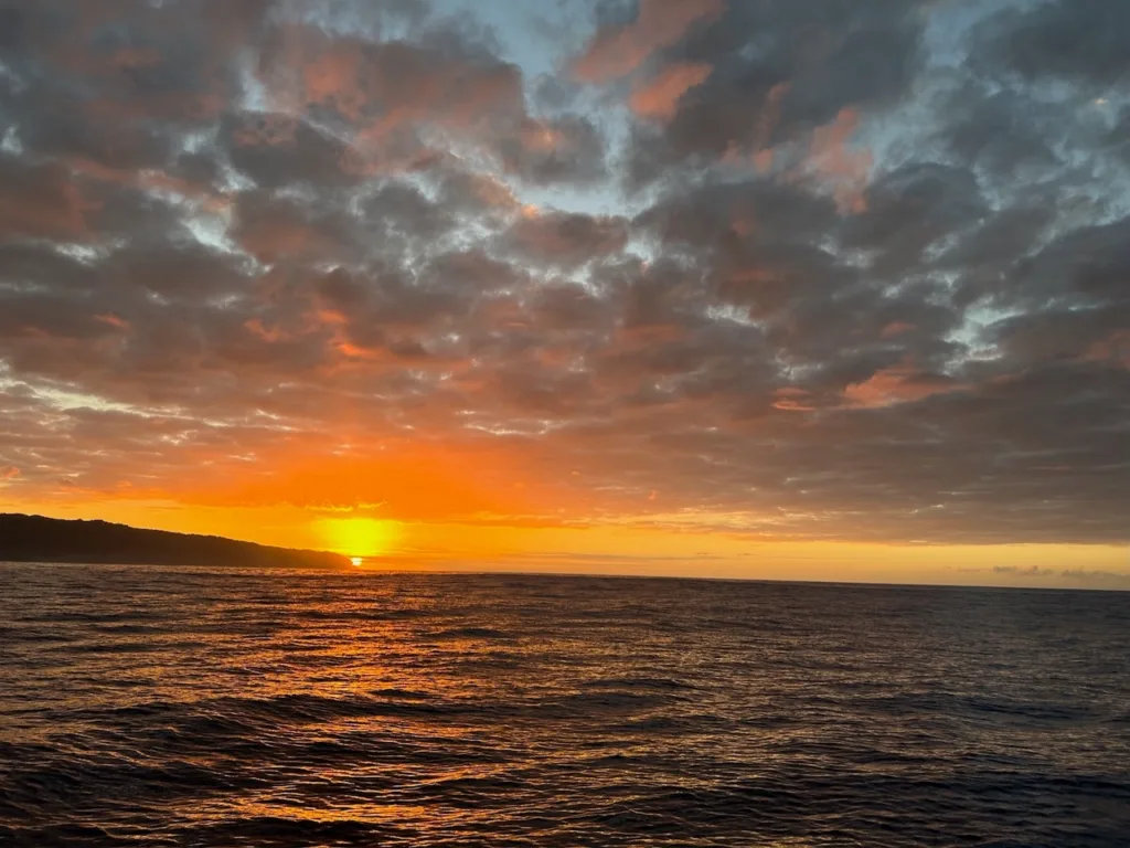 Sunset cruise boat sailing on calm ocean waters at dusk
