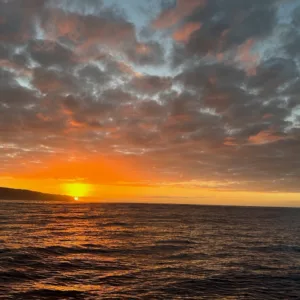 Sunset cruise boat sailing on calm ocean waters at dusk