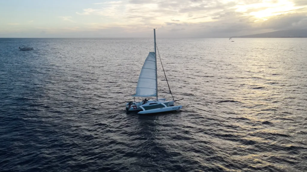 Sailboat gliding across calm waters at sunset in Waikiki