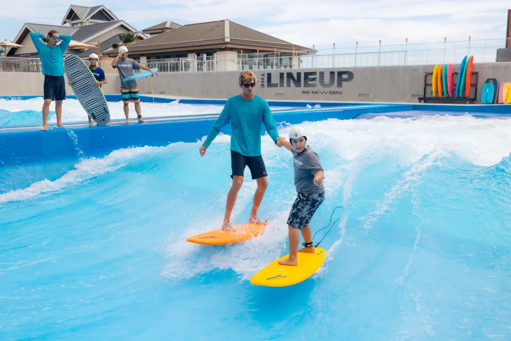 Surf instructor teaching beginner on gentle ocean waves