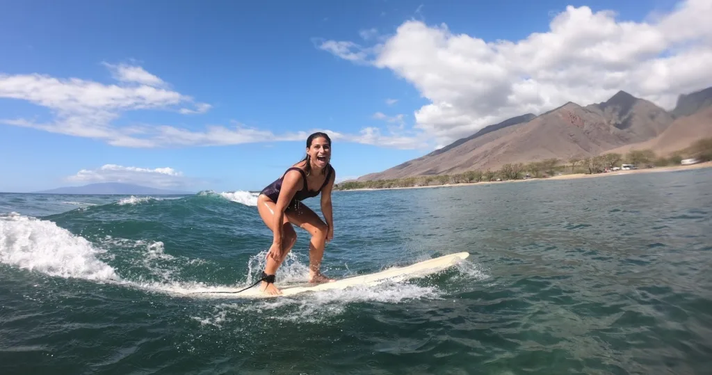 Surf instructor assisting student on gentle ocean waves