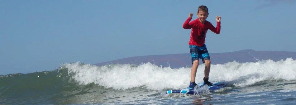 Children catching waves during beginner surf class