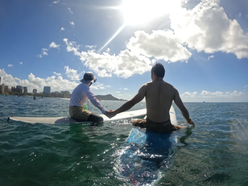 Instructor teaching beginner how to surf on gentle waves