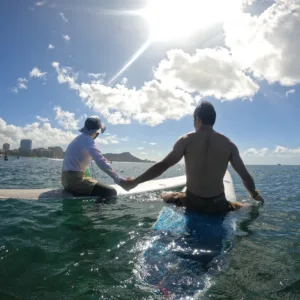 Instructor teaching beginner how to surf on gentle waves