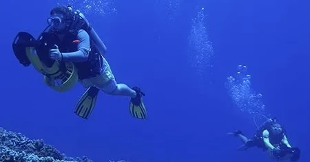 Scuba diver using underwater scooter to explore coral reefs