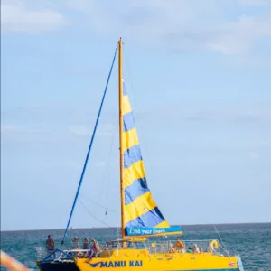 Sailboat gliding across calm waters at Manu Kai Harbor sunset