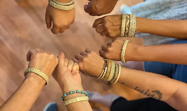 Hands weaving a traditional Lauhala bracelet in a craft class