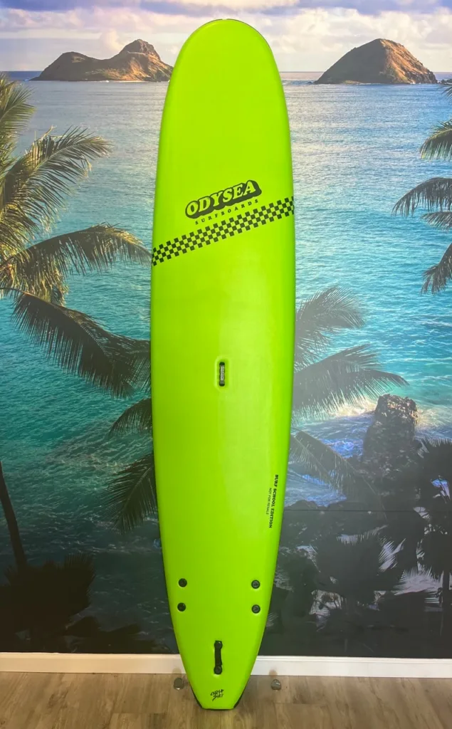Green 9 foot Odysea surfboard on sandy beach