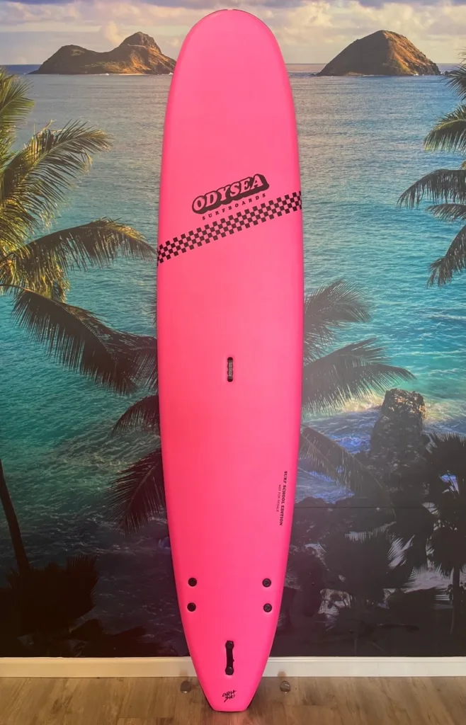 Pink 9 foot Odysea surfboard leaning against palm tree