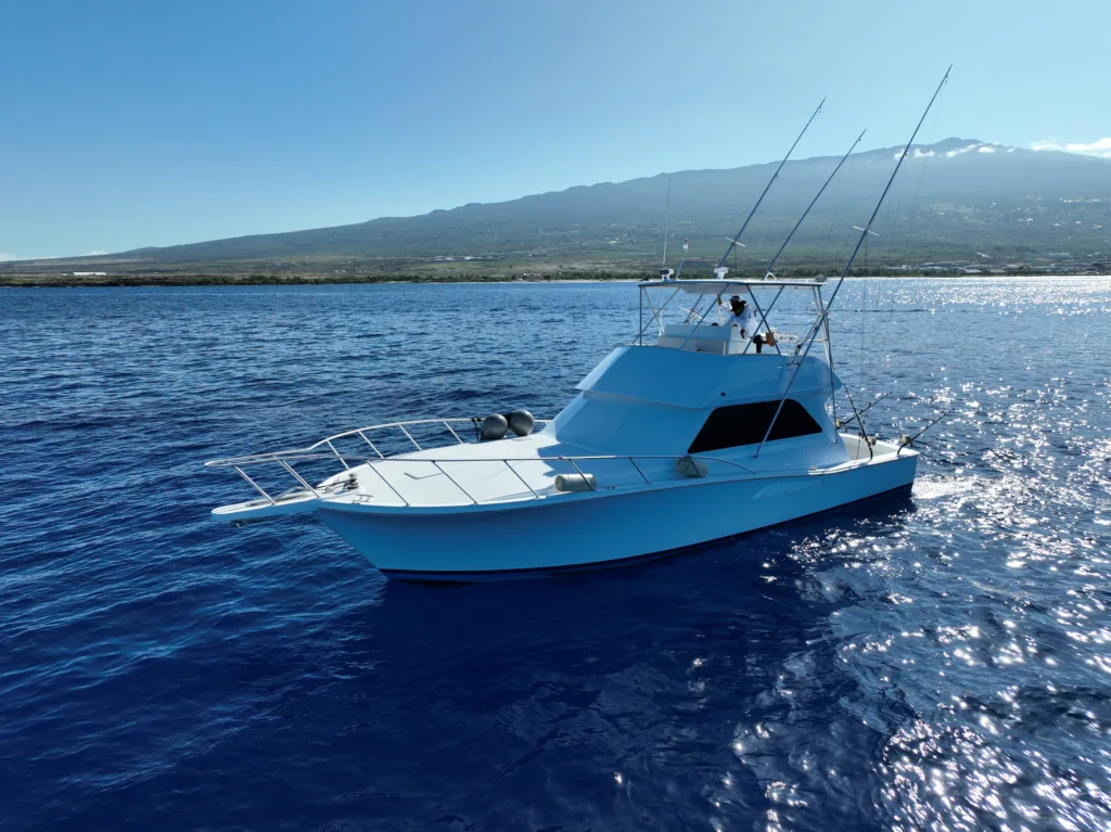Private fishing boat cruising Kona coastline at sunrise