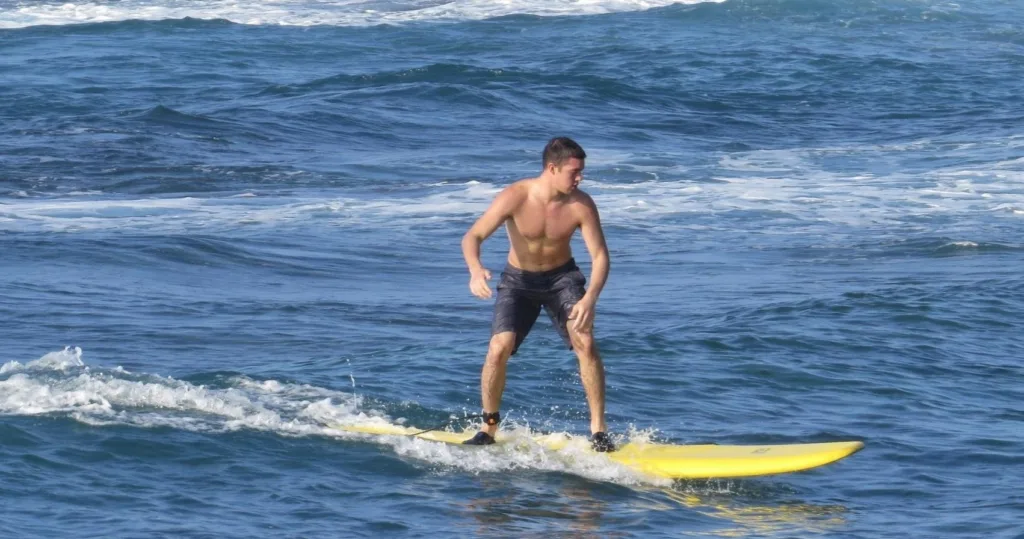 Beginner surfer catching small wave at Poipu beach