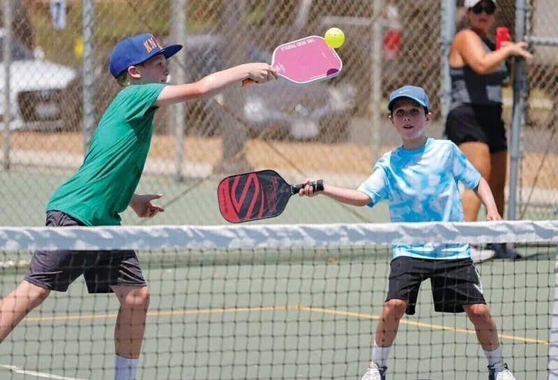 Kids practicing pickleball skills on outdoor court