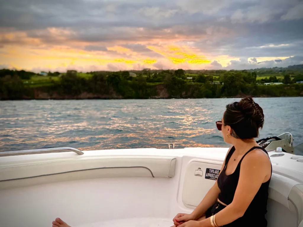 Boat cruising Hilo Bay at sunset with colorful sky