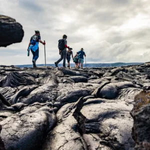 Hiker trekking volcanic terrain with steam vents nearby
