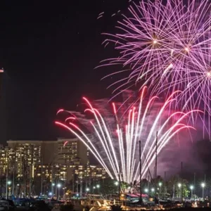 Kayakers paddling at sunset with fireworks lighting the sky