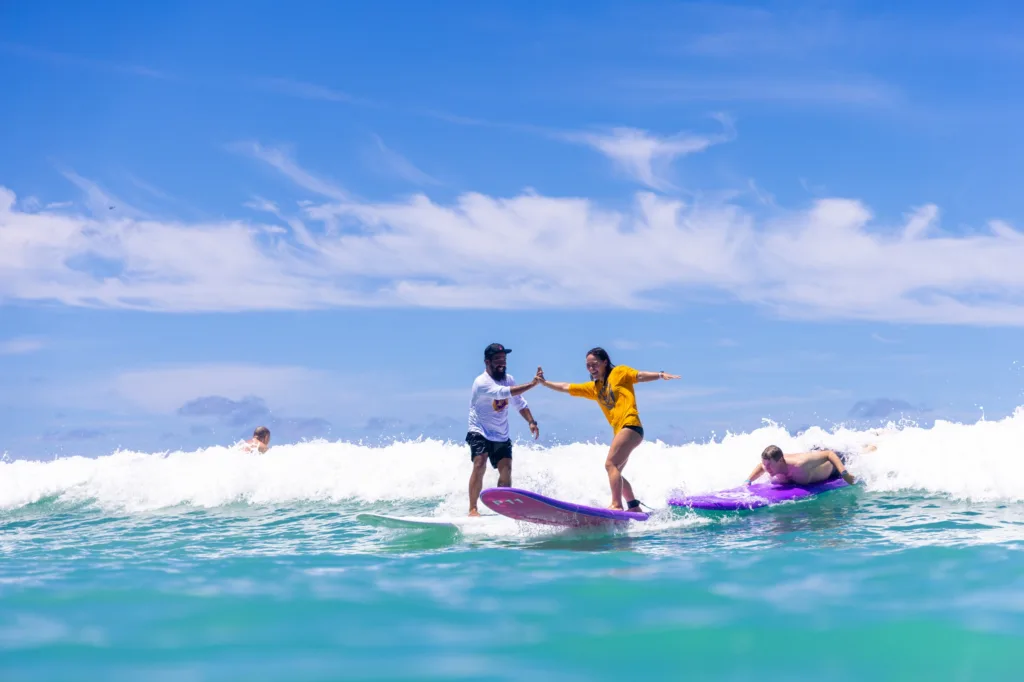 Instructor giving individual surf lesson to beginner surfer