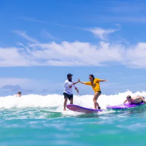 Instructor giving individual surf lesson to beginner surfer